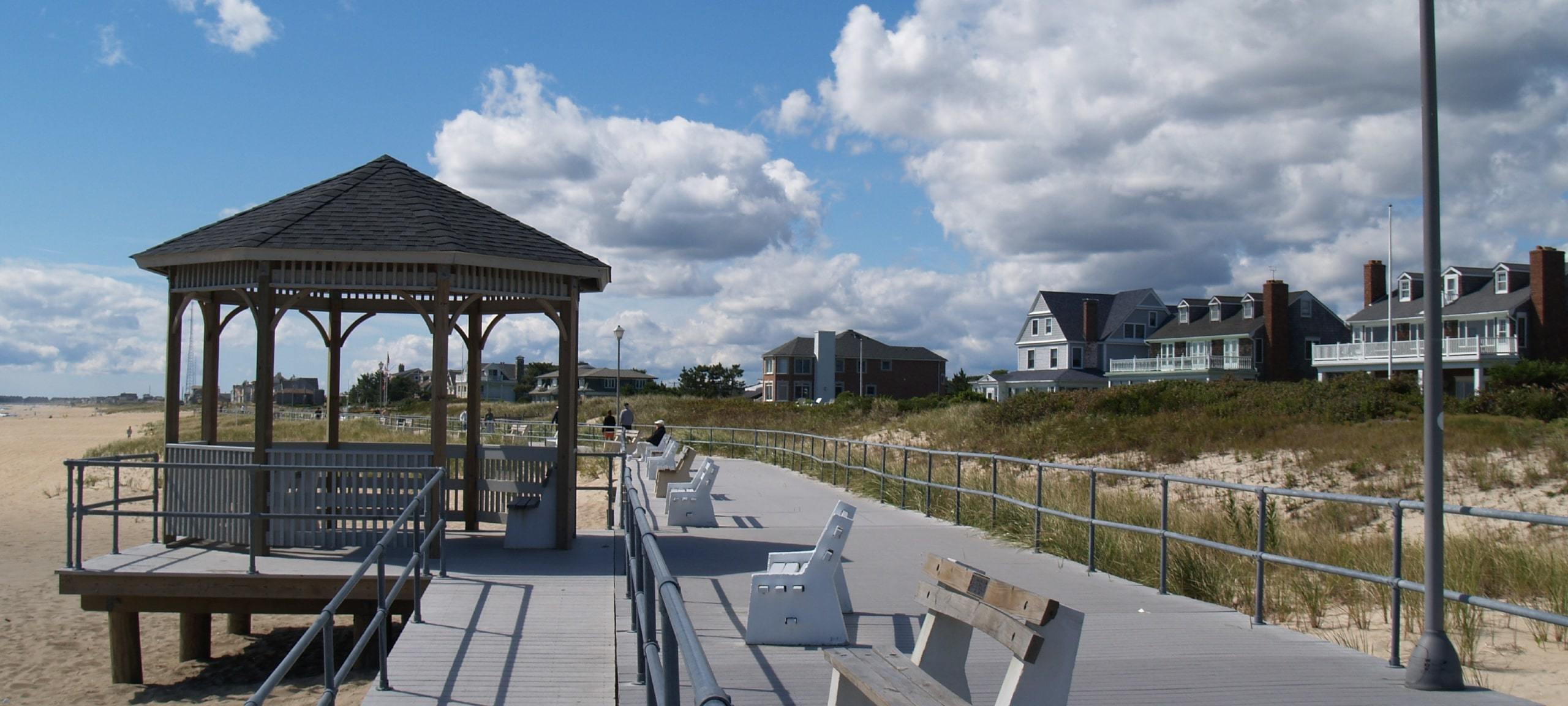 Iconic boardwalk on a sunny day with homes in distance in Sea Girt, NJ