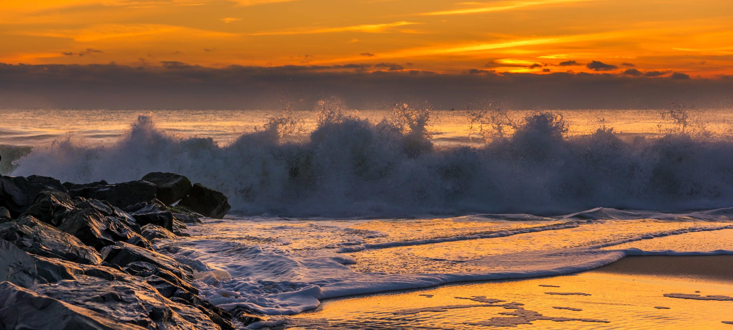 Waves crashing upon Bay Head, NJ rocks during yellow sunrise