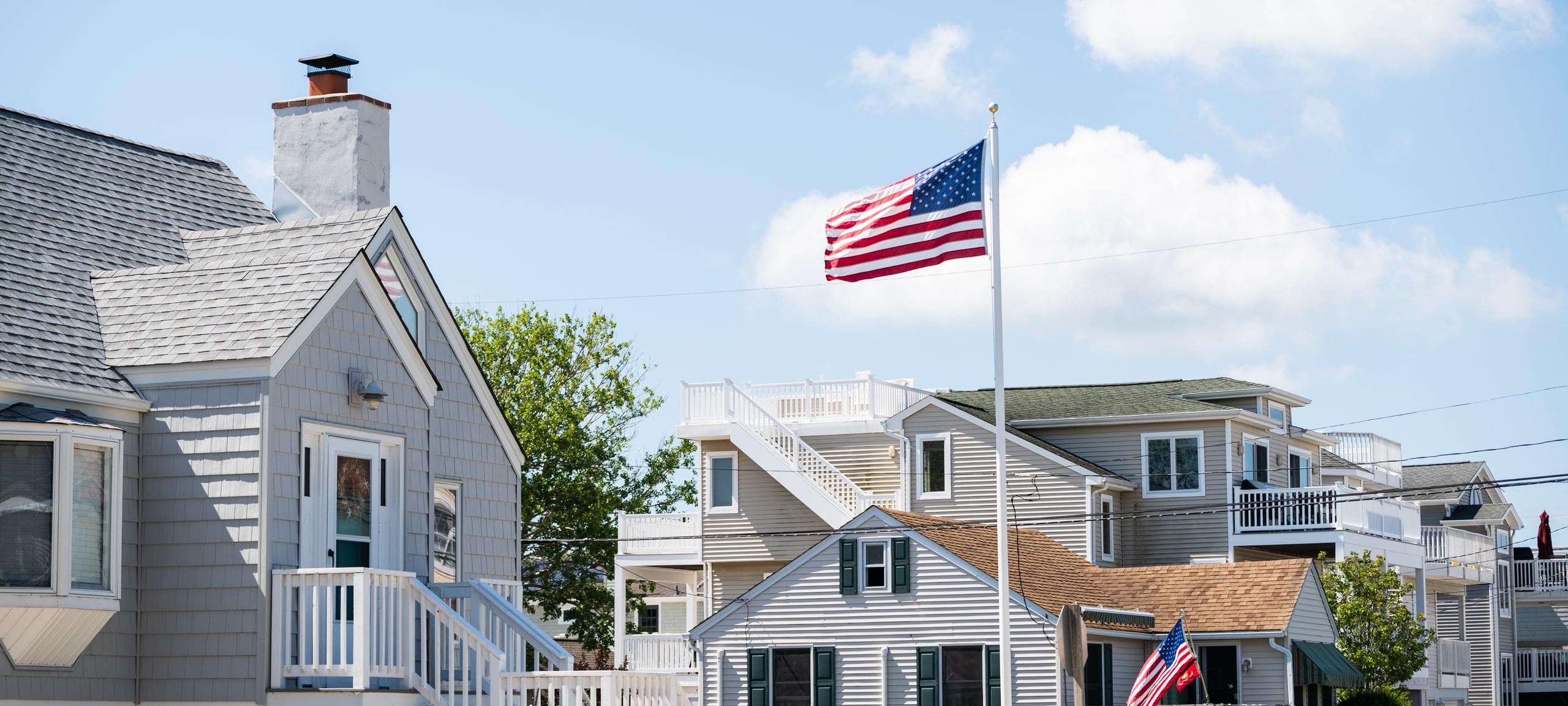 Bright coastal style homes in Jersey Shore community with American flag